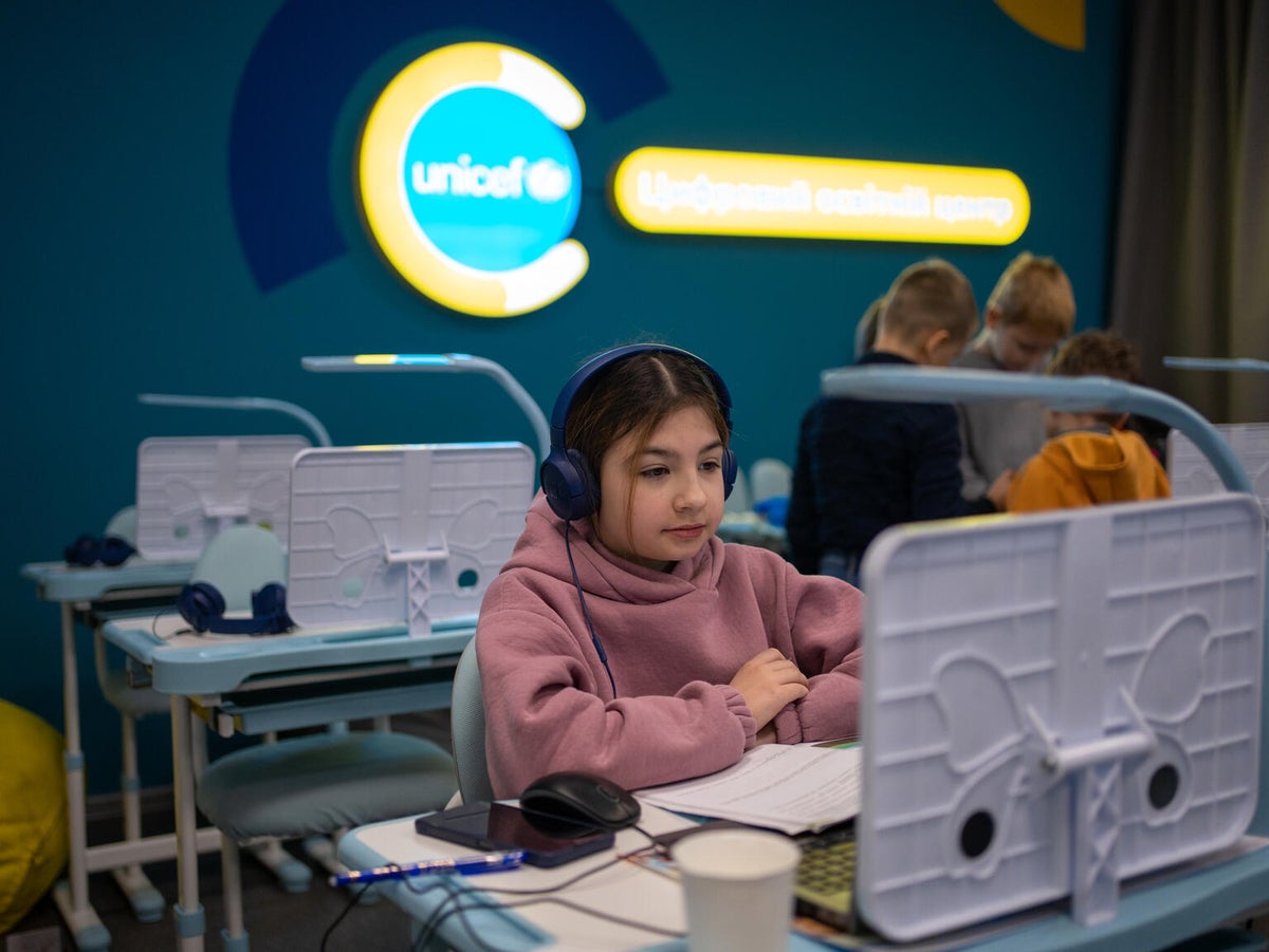 A young girl wearing headphones sits at a computer at a UNICEF-support Digital Learning Hub in Ukraine.