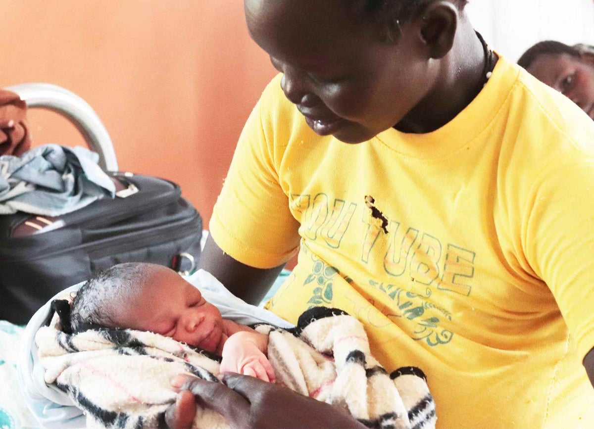 Christine carries her newly born baby in the maternity ward of a Health Centre that serves South Sudanese refugees and host communities