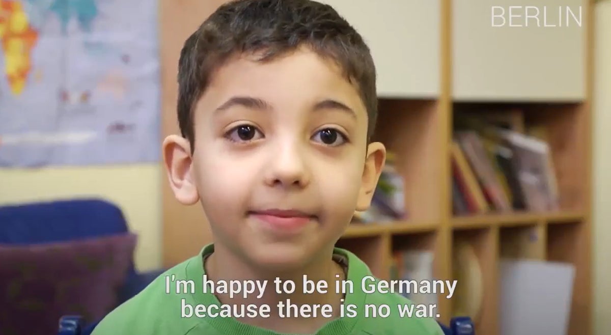 A young boy in a green top. The caption reads "I'm happy to be in Germany because there is no war." 