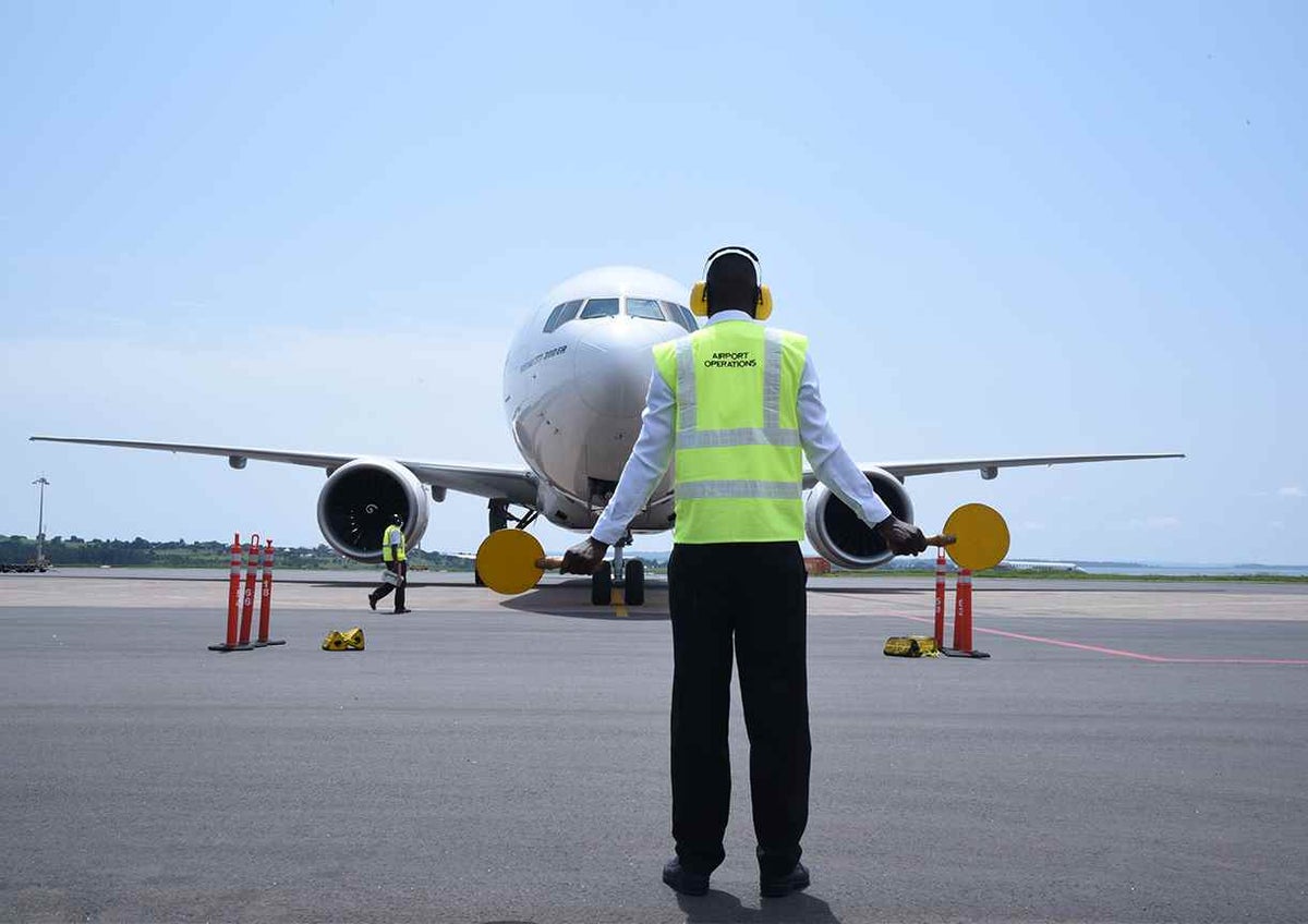 A marshaller signals a plane carrying a shipment of 864,000 doses of the AstraZeneca COVID-19 vaccines in Uganda.