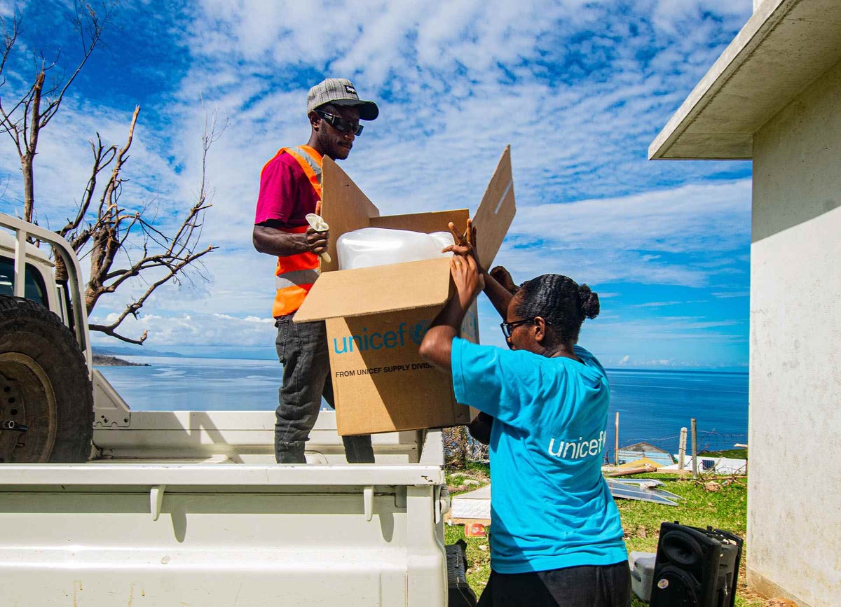 A volunteer helps a UNICEF workers unload water and sanitation supplies in Fiji in the aftermath of Tropical Cyclone Harold.