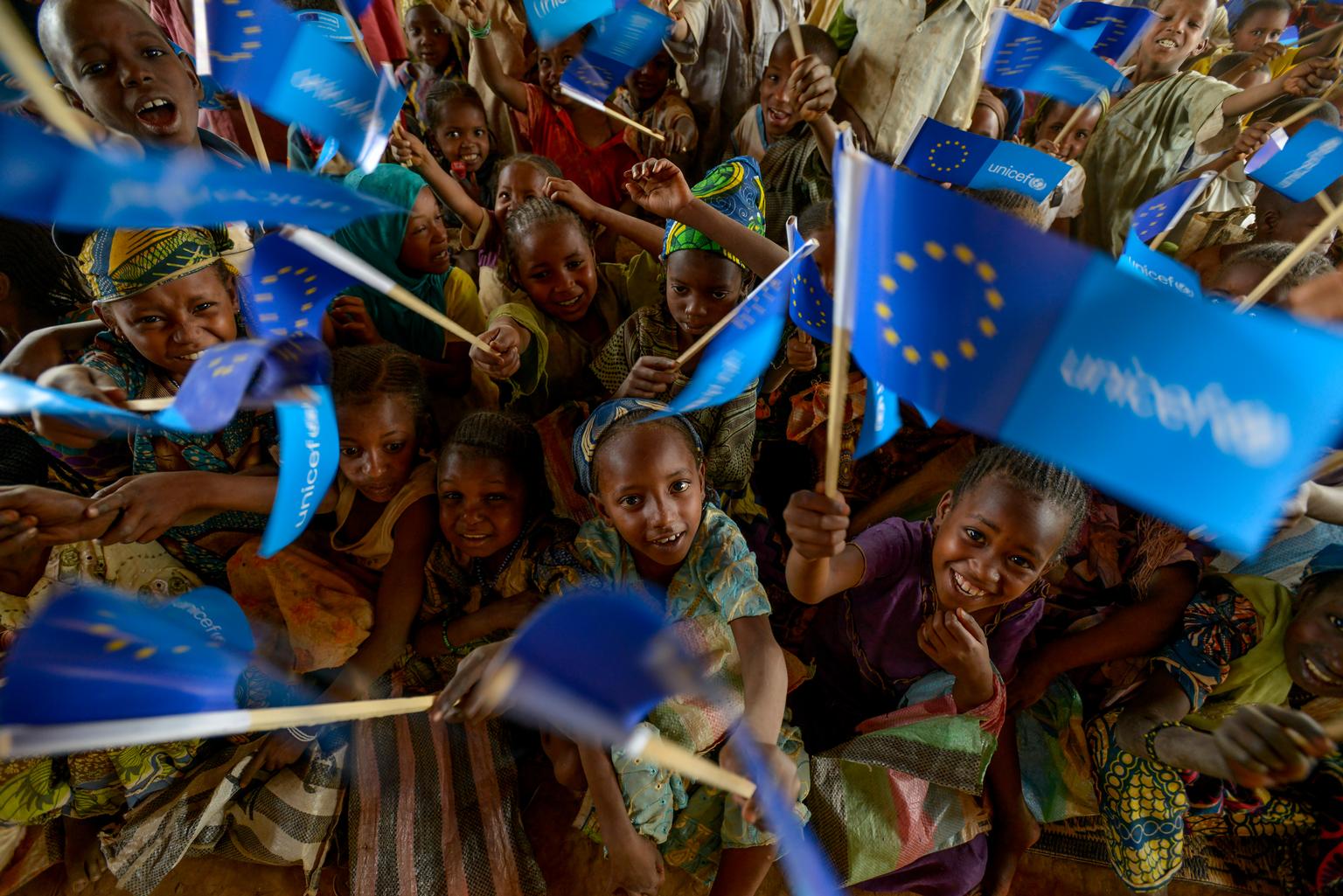 On 2 March 2015, children wave small flags with the European Union (EU) and UNICEF logos in a primary-school