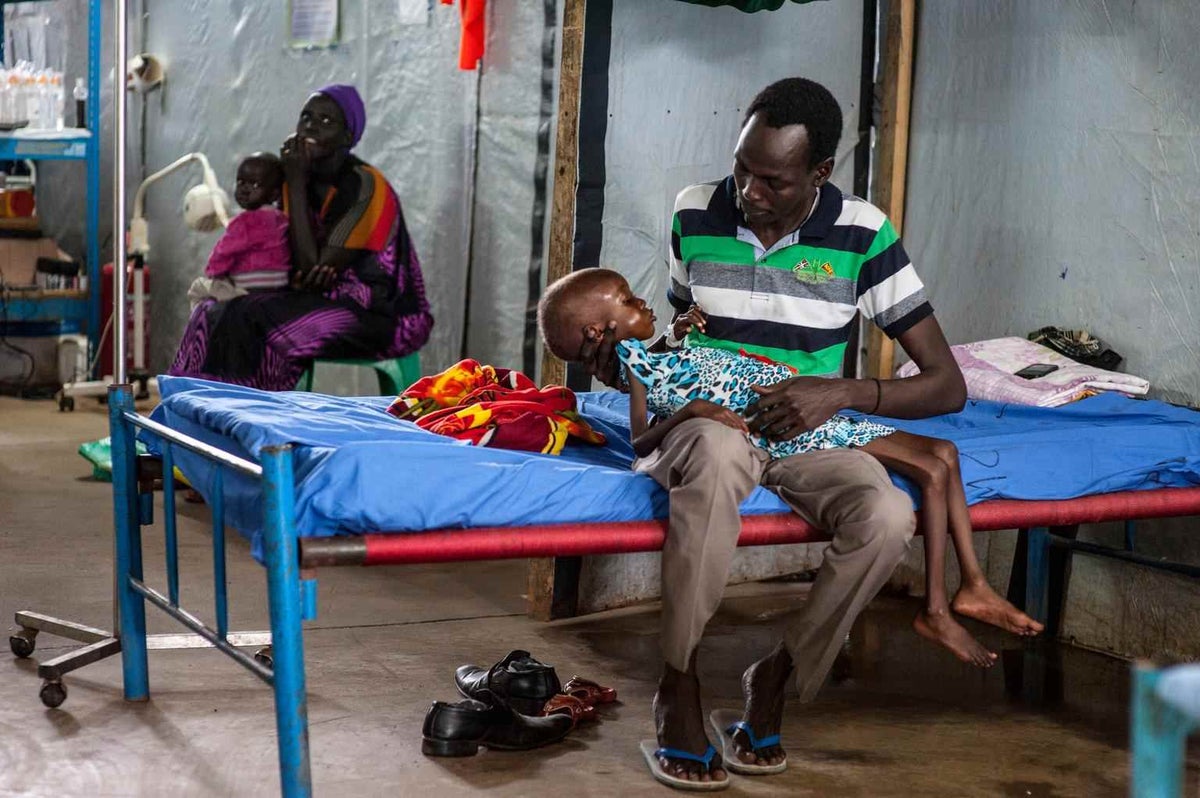 Father holds his sick daughter in a hospital bed.