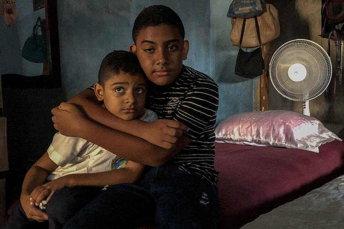 Jairo (right), 13, sits with his brother Marvin, 7, in the bedroom that they share with their mother. Jairo is bullied in school. 