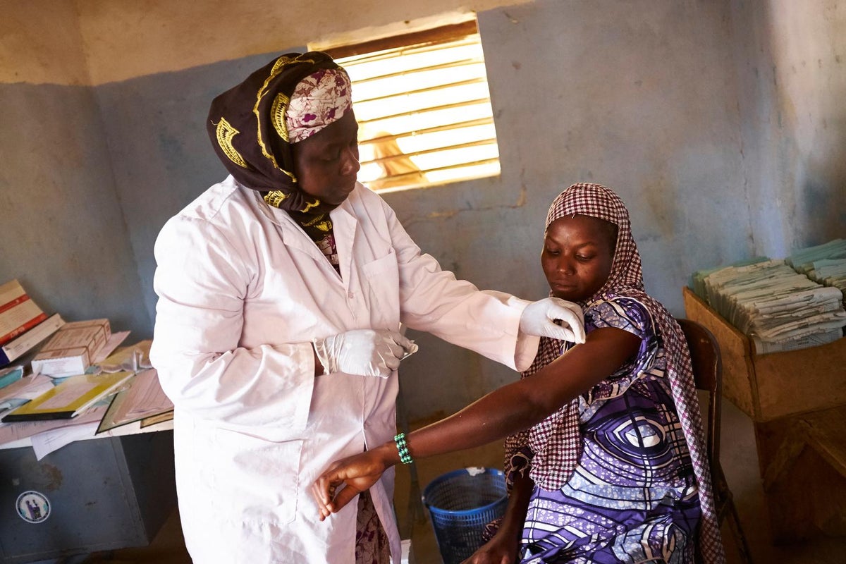 A health care worker applies a vaccine to a pregnant woman