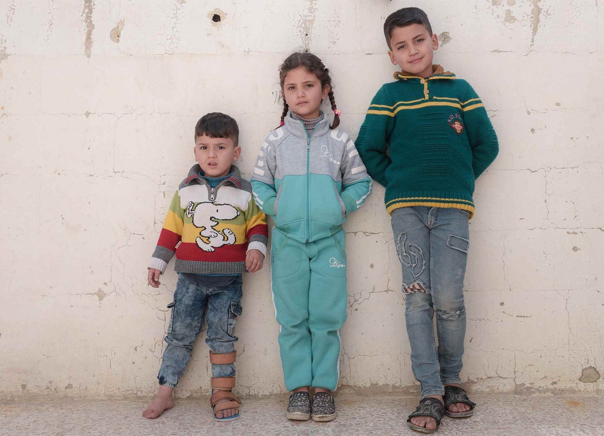 Mohammad, Nada and Anwar pose for a photo outside their home in Erbin, Syrian Arab Republic.
