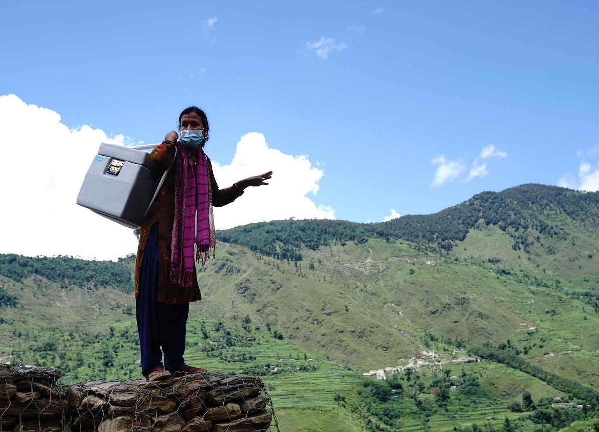 Birma carries COVID-19 vaccines to a health post in in Nepal's remote far-west, where she works as a support staff. 