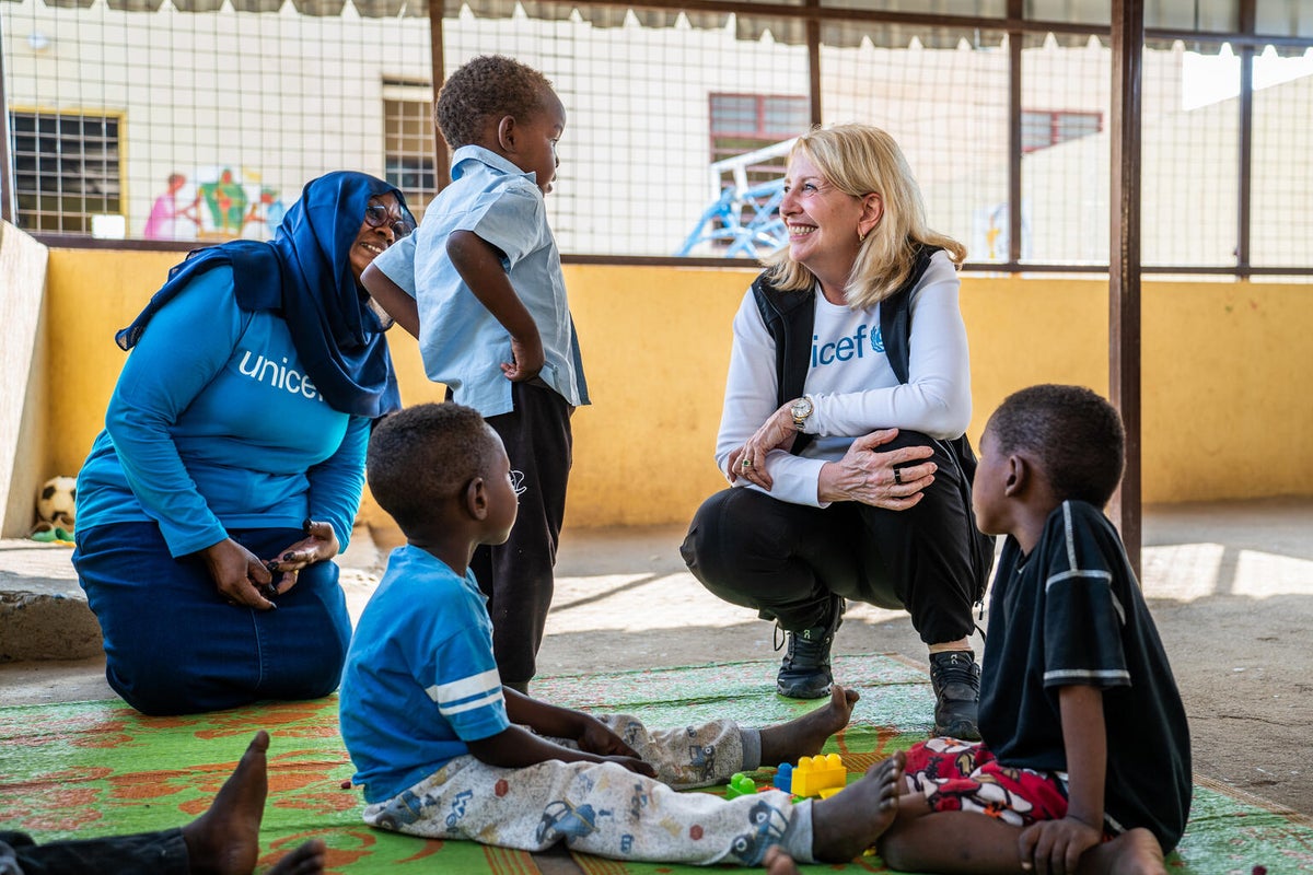 UNICEF Executive Director talks to young boy as two other children and a UNICEF worker watch on.