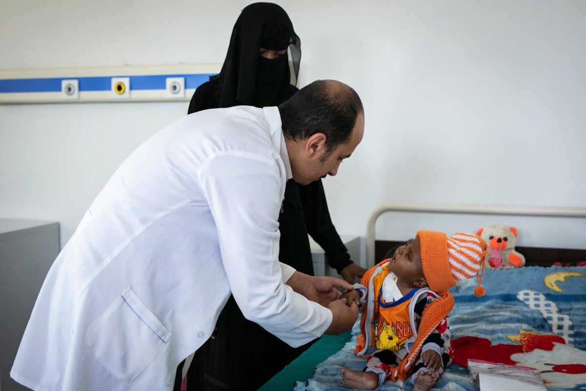 A little boy is being assessed by a doctor. The boy's mum is next to him.