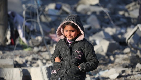 Young girl in Gaza sitting among rubble