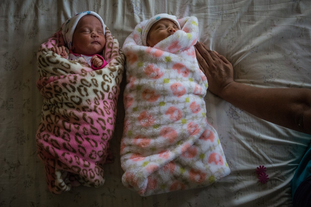 Two newborn babies sleeping on a bed