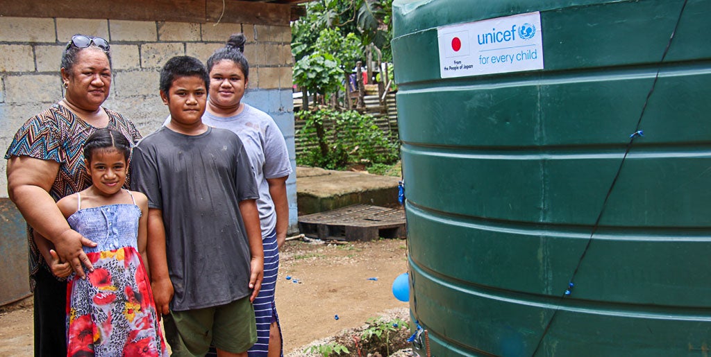 Pele and her three children stand with their new water tank.