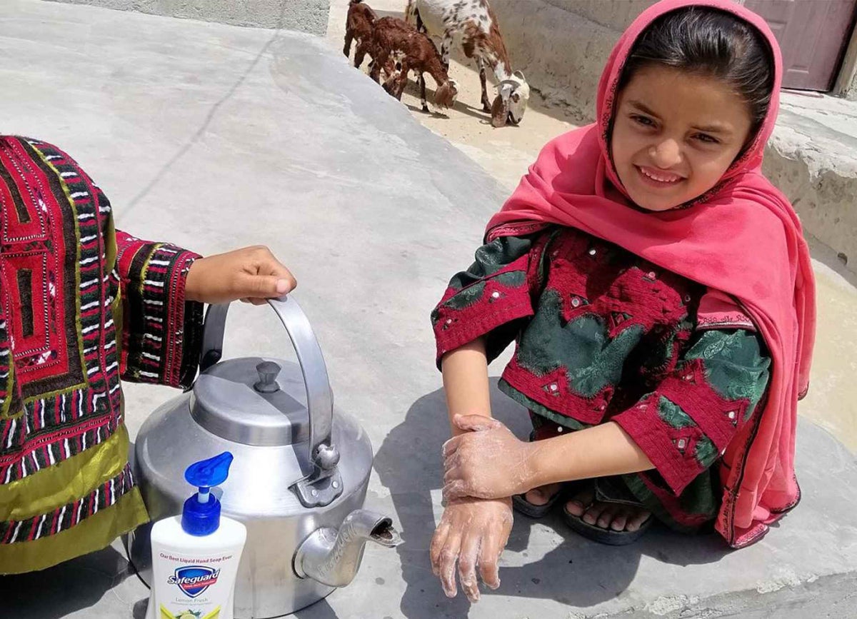 Mariam, 8, washes her hands at a handwashing station that her cousin Najeeba created at her home
