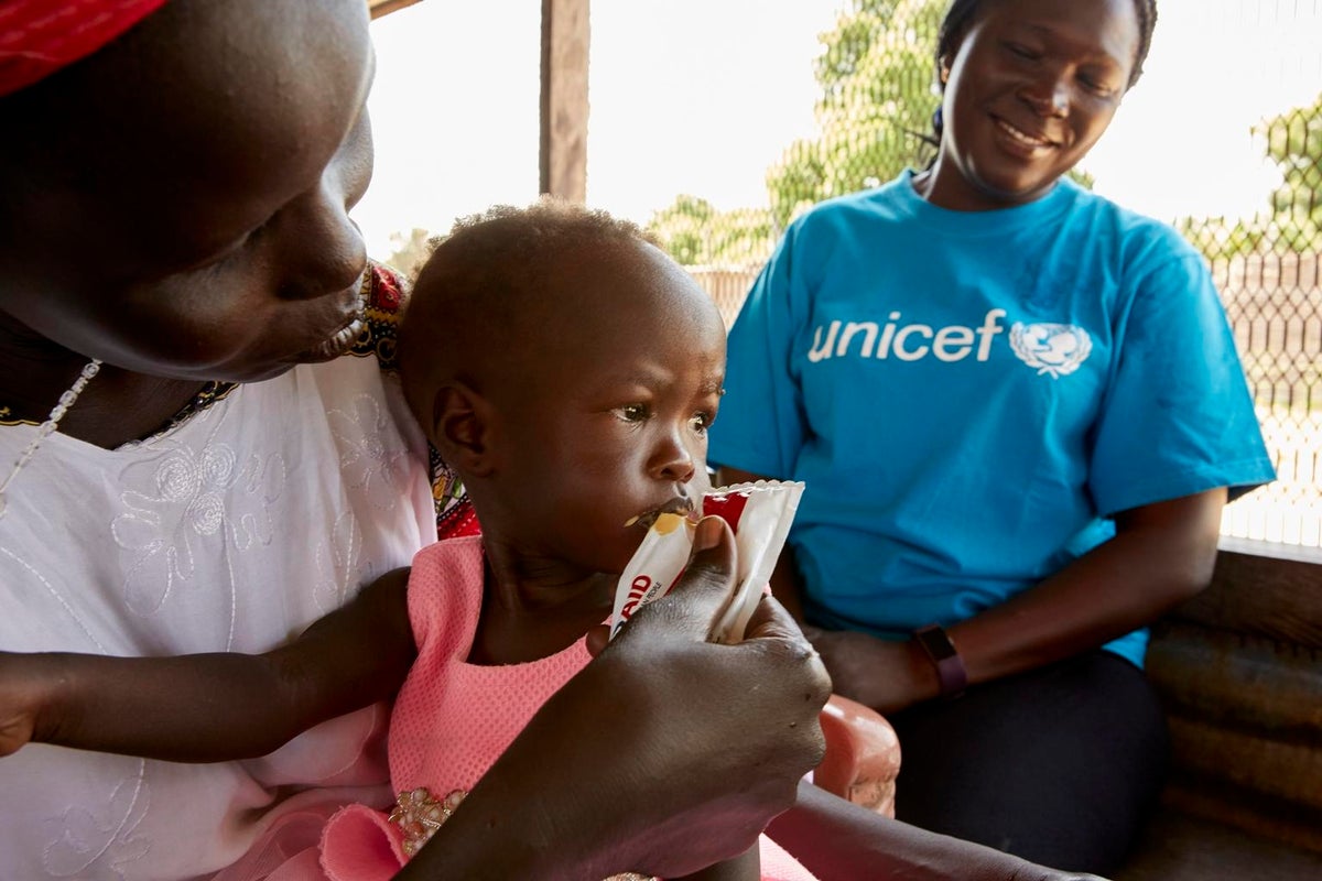 A mother is feeding her daughter with a sachet food.