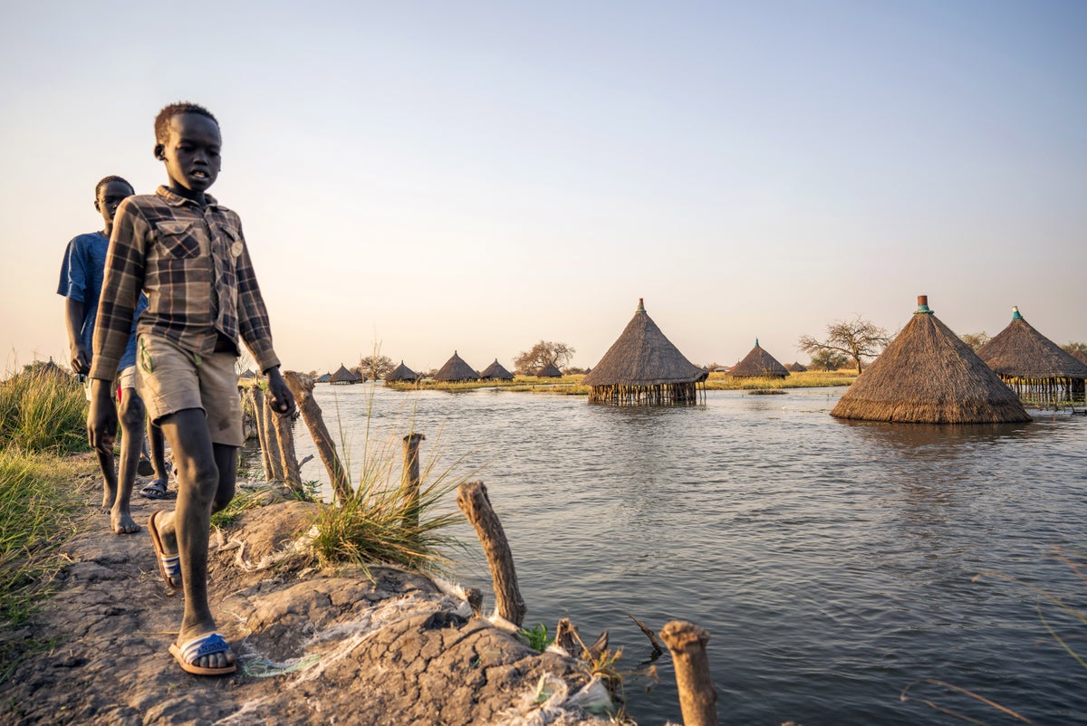 Boys walk along the man-made dyke separating flood water and submerged houses from relatively dry land in the village of Panyagor, South Sudan.