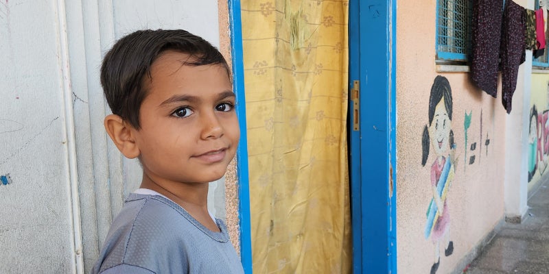 Child standing in front of classrooms where they are sheltering during the Gaza crisis