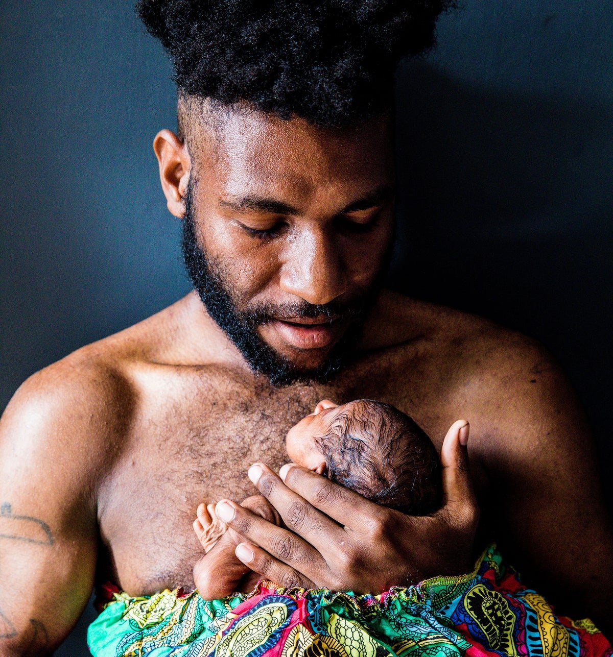 A father holds his newborn baby against his chest. 