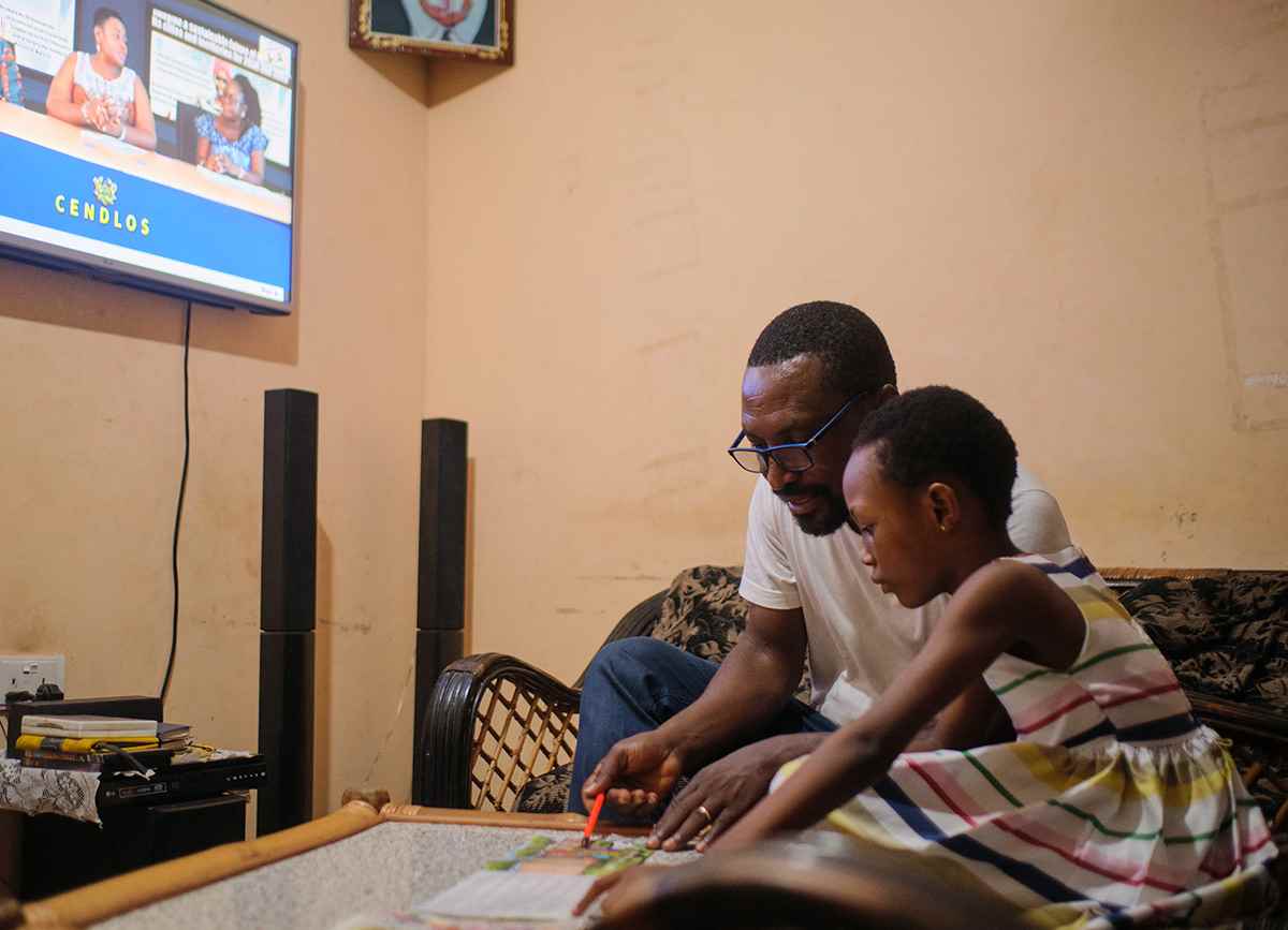 Ten-year-old Deborah reads learning materials with her father in Ghana.