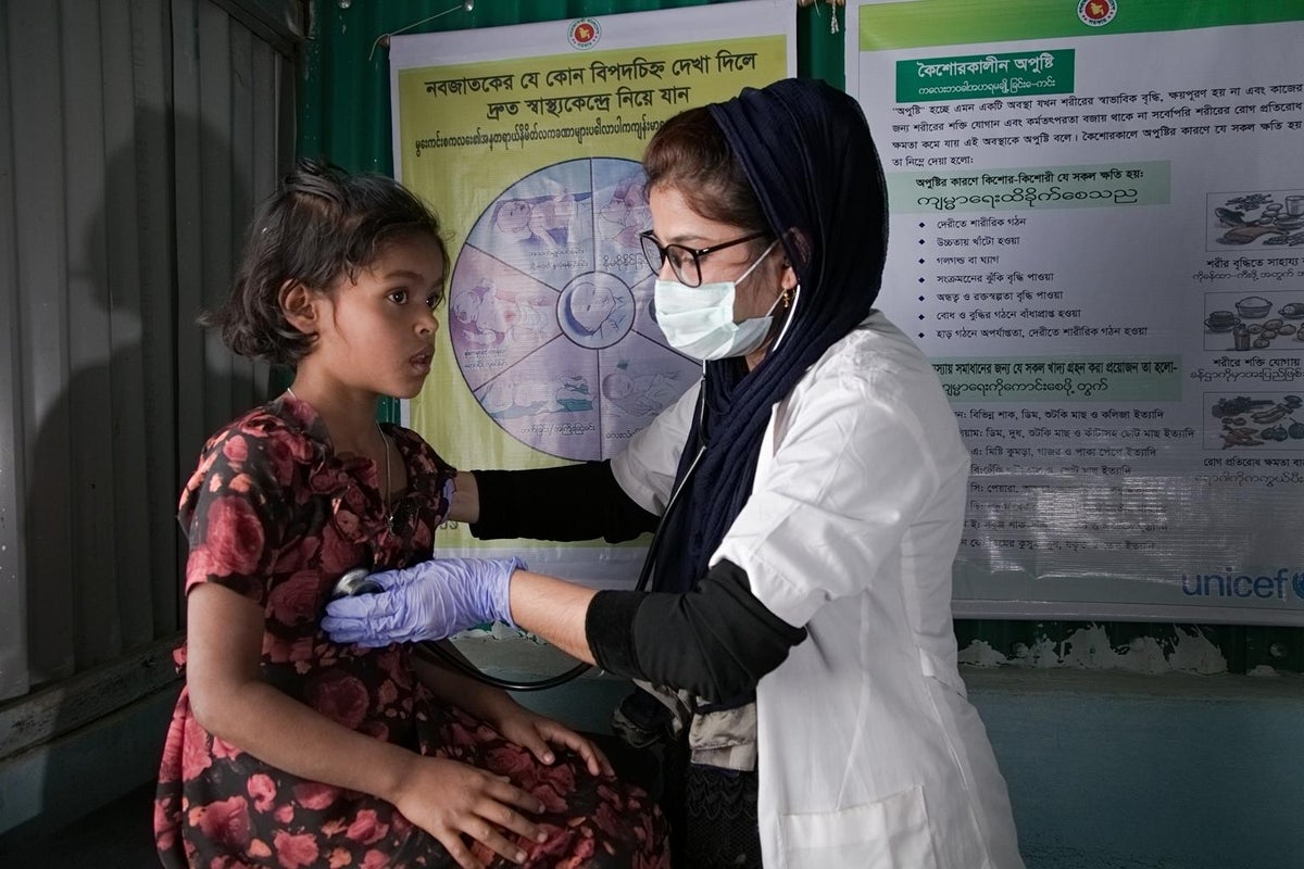 A doctor assesses a girl with a stethoscope.