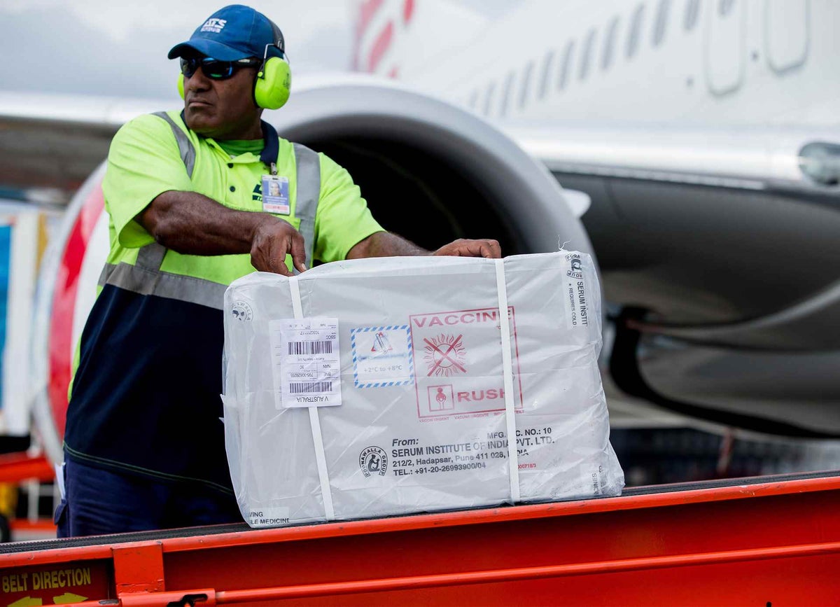 Measles vaccines are unloaded by airport personnel in Fiji before being inspected and transferred onward. 