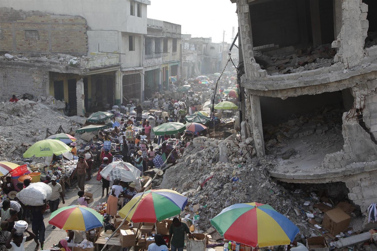 A destroyed road. A lot of people walking on the rubble.