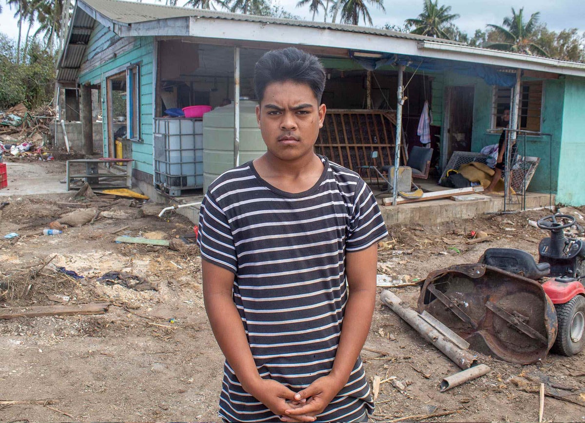 Saia, 15, stands in front of his home on Tongatapu, Tonga’s main island, showing the damage caused by volcanic eruption and tsunami.