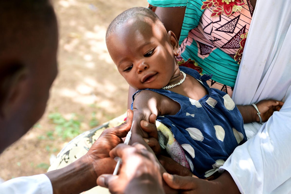 A baby girl looking at at a needle vaccination on her arm
