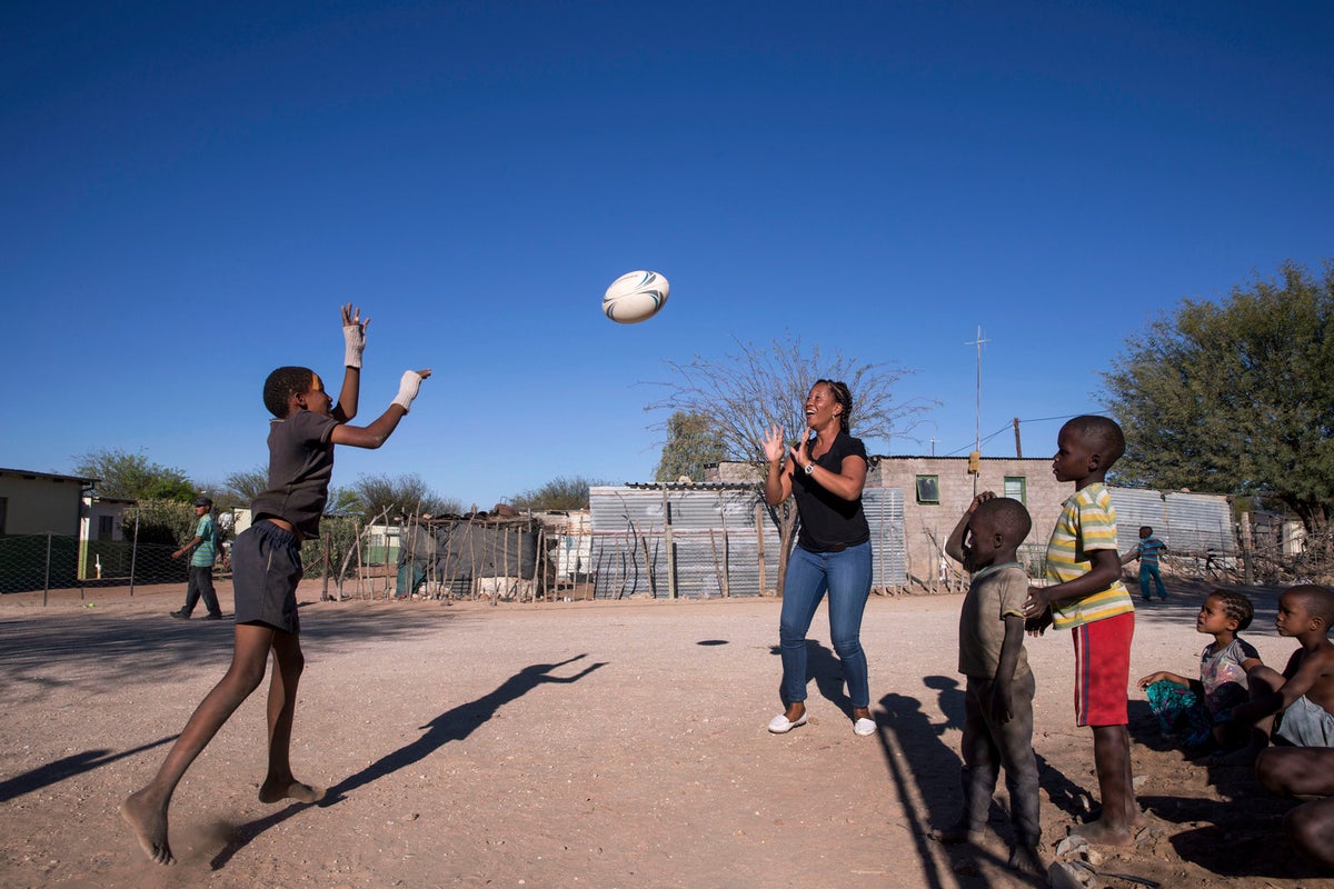 Livey and a boy play with a rugby ball.