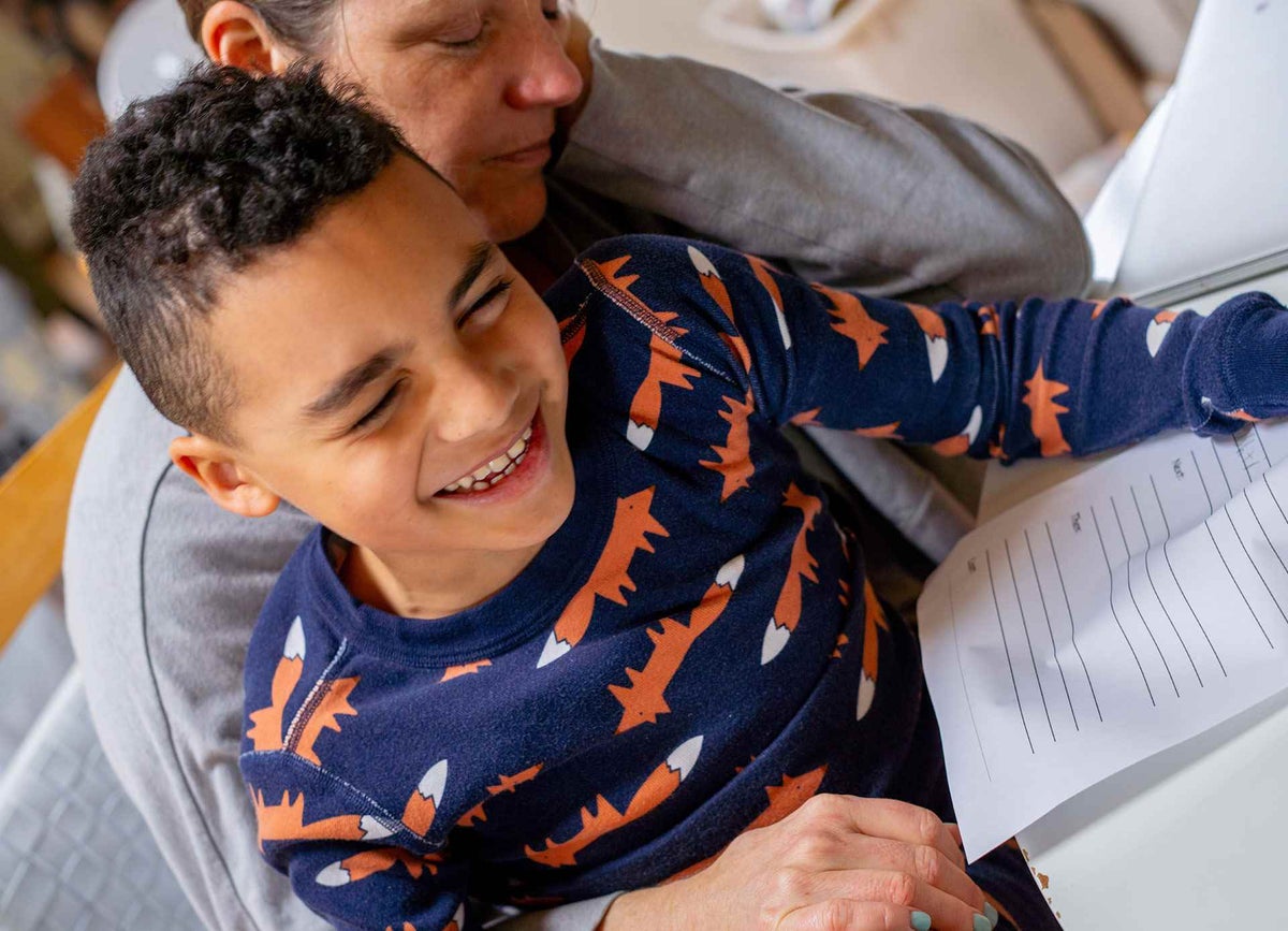 Boy laughing while sitting on his mothers lap