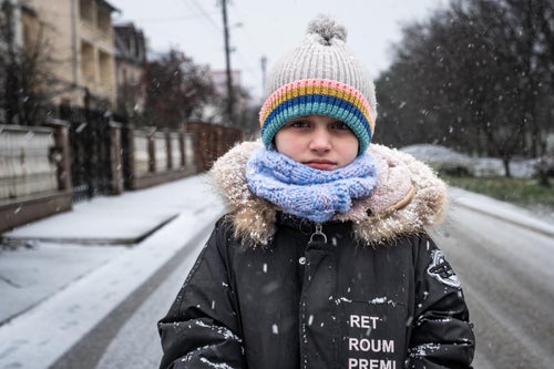 A young girl rugged up and standing in the snowy streets of Ukraine.