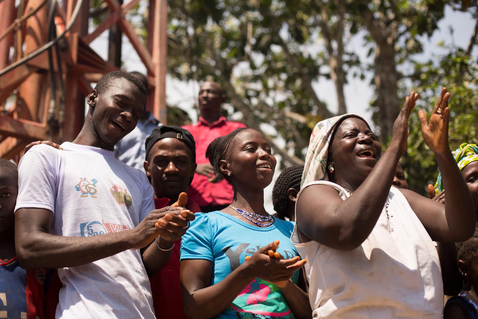 On 13 May 2015 in Guinea, onlookers applaud and celebrate after a borehole drilling rig