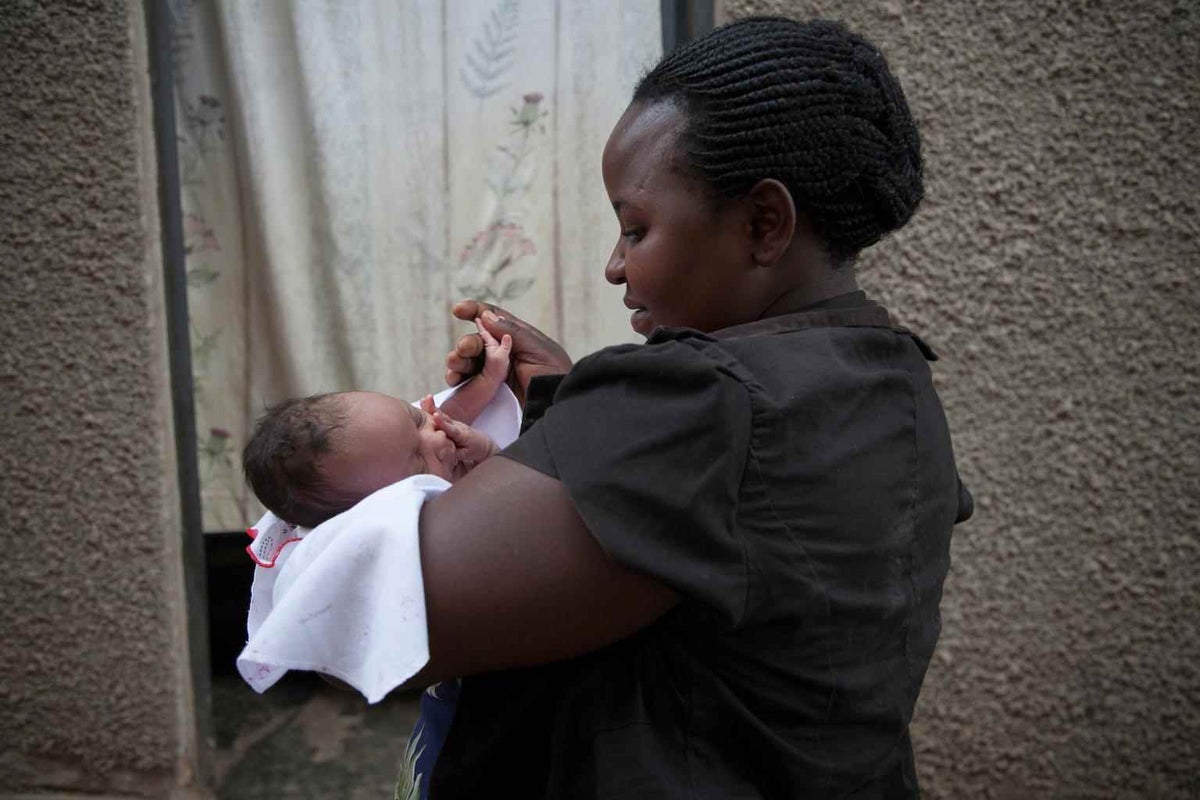 Mantume Christine holds her newborn baby girl outside her family home in Central Uganda in 2014.