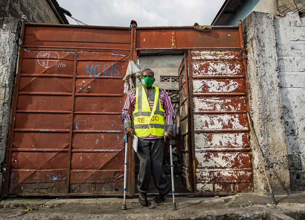 A man wearing a mask and HI-Vis standing in front of a maroon gate.