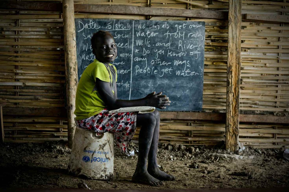 Ten year-old Nyanyang sits on a broken UNICEF water bucket at school. 