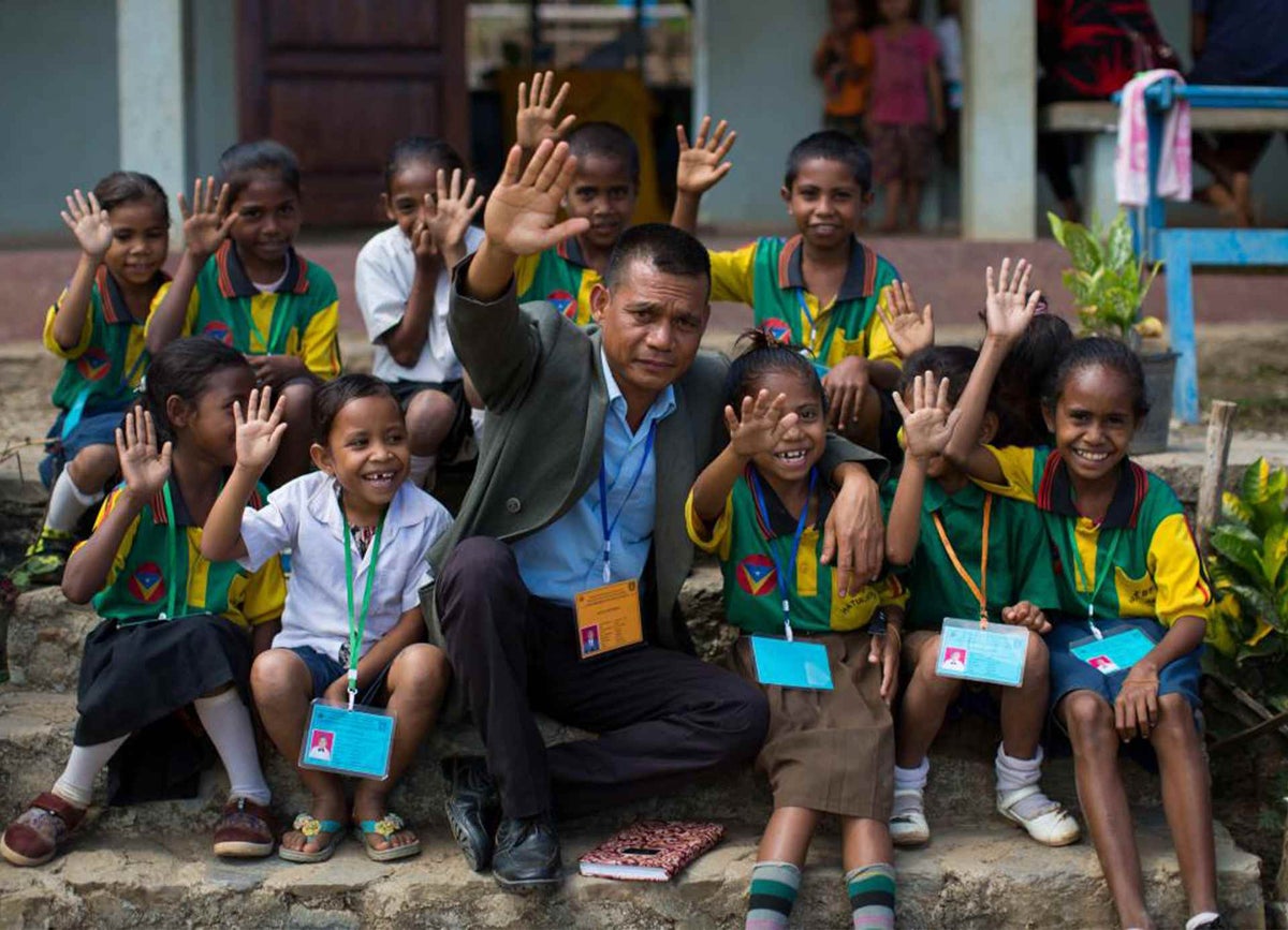 Children and School Coordinator Nicolau wave happily at their school located in a remote village in Ermera municipality.