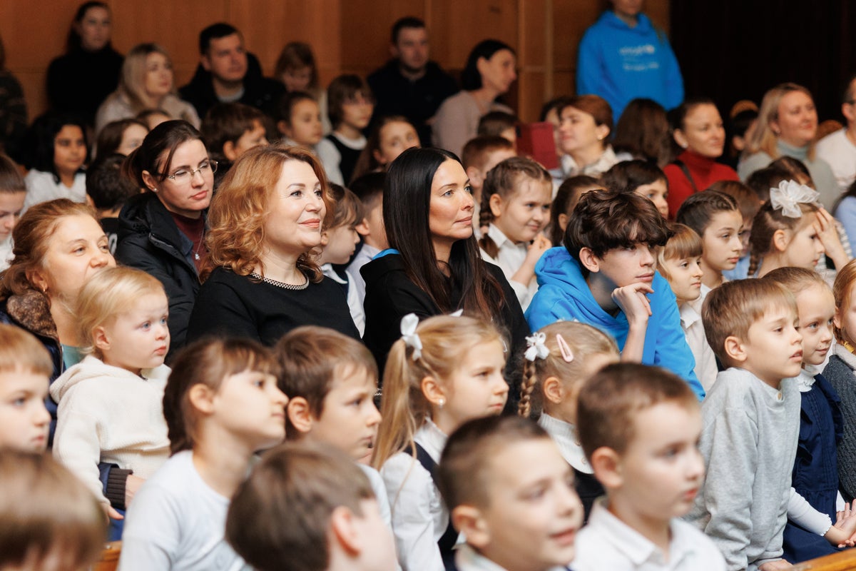 A group of adults and children watching a puppet show. 