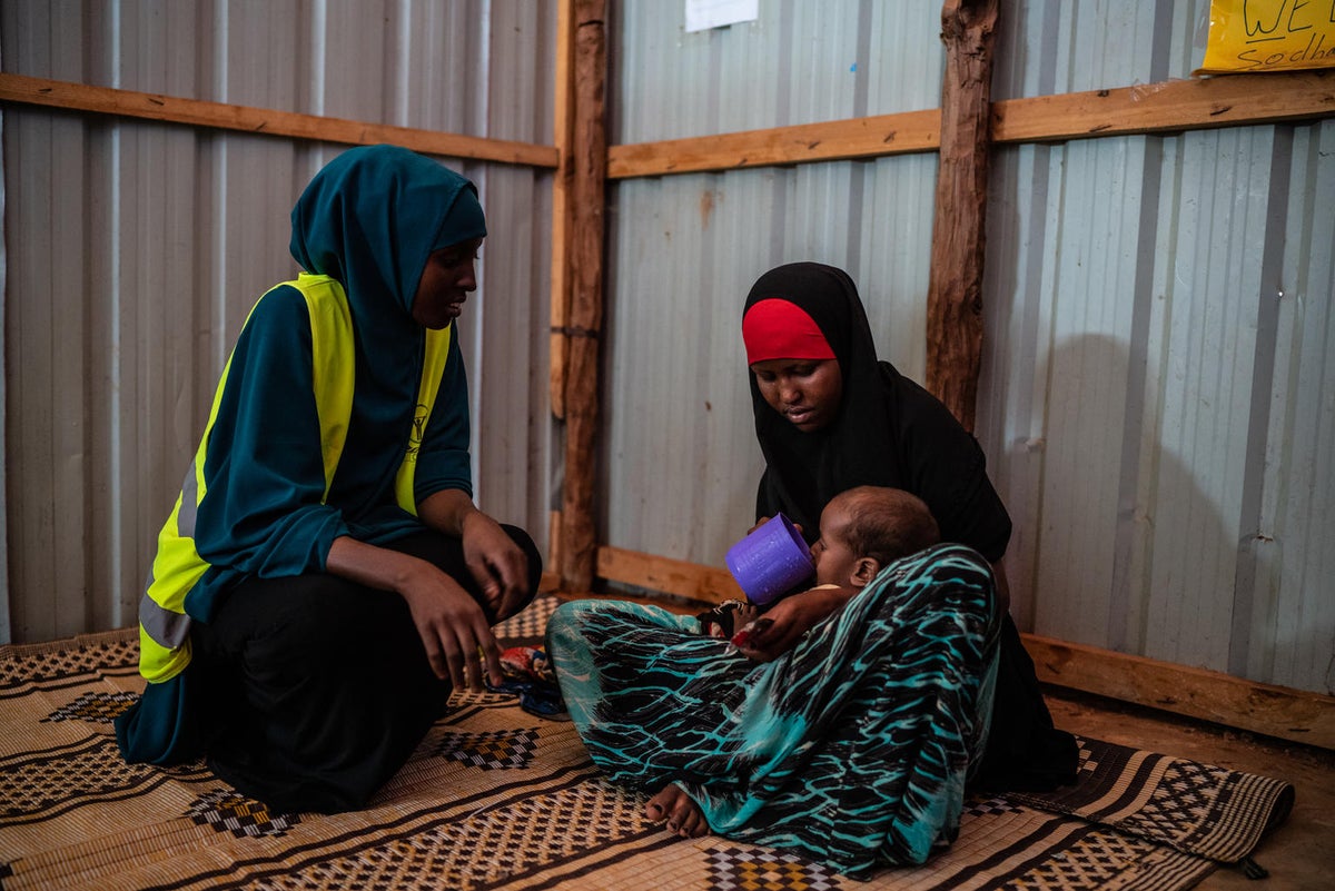 A health worker watches on as Farhir, 20, gives water to her son.