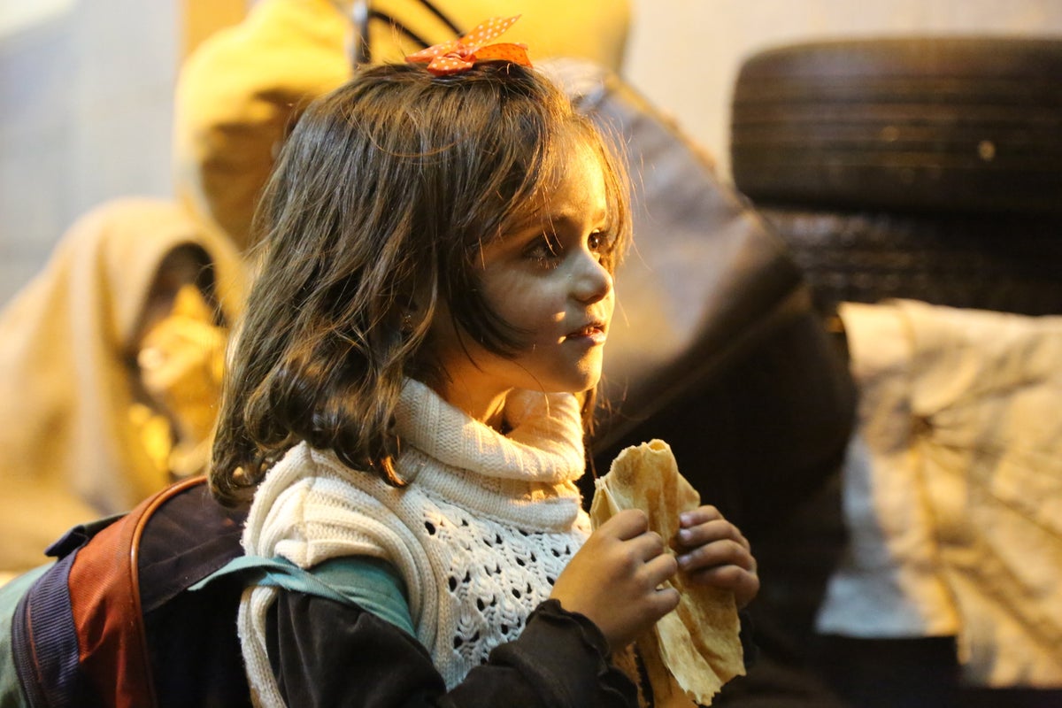 A young girl is holding a piece of bread