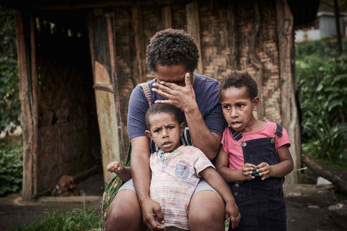 Rebecca, 32, cries while holding her two children: Dre Druagl, 4, and Willande, 3. Rebecca works very long hours as a nurse at the local clinic. She wishes she had more time to spend with her children