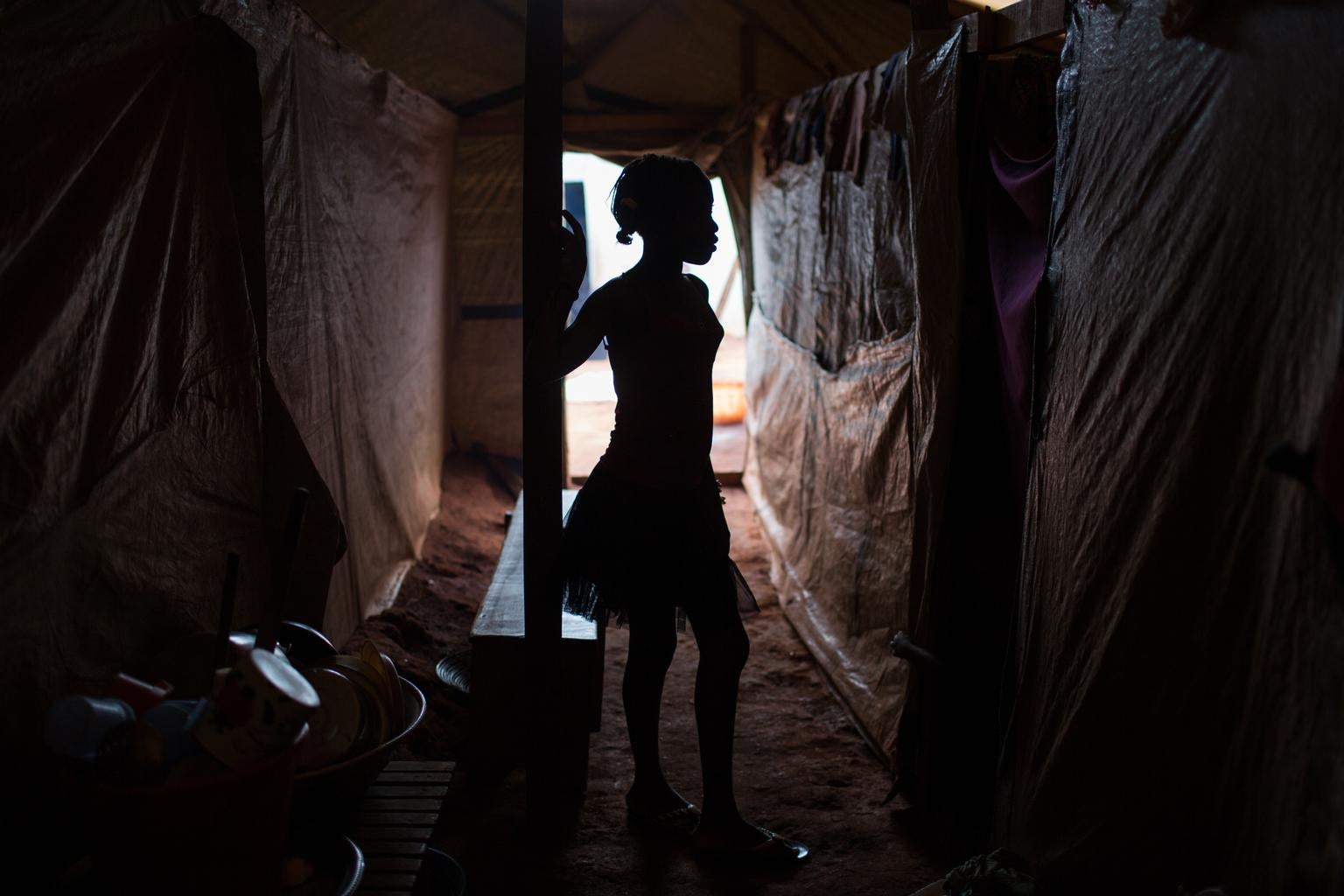 On 23 June 2015 in the Central African Republic, Alison, 14, stands beneath a makeshift shelter