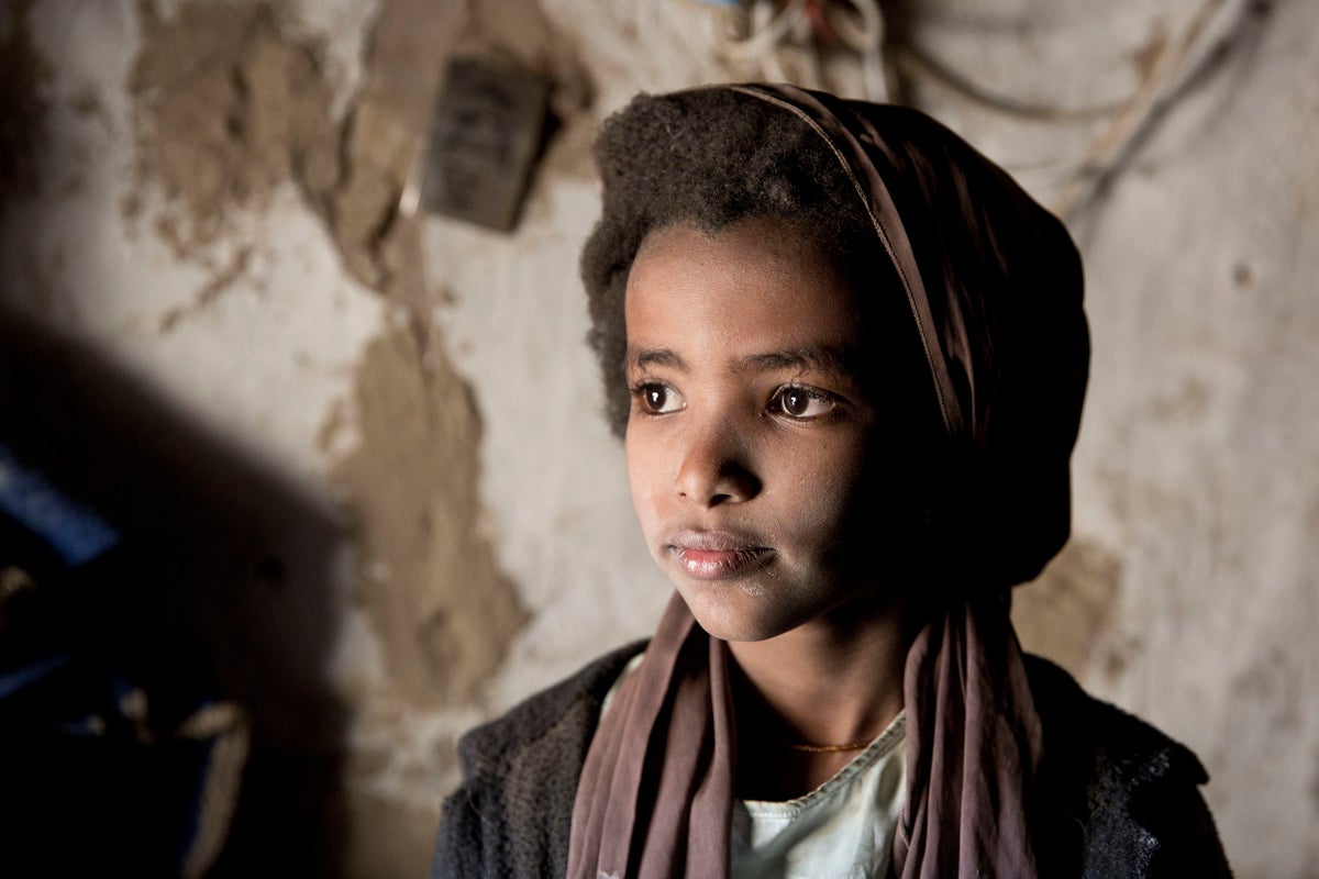 A boy with dust on his face looks at a window.