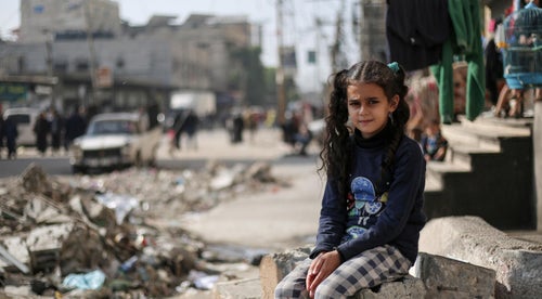 A young girl in Gaza sitting amongst ruined buildings