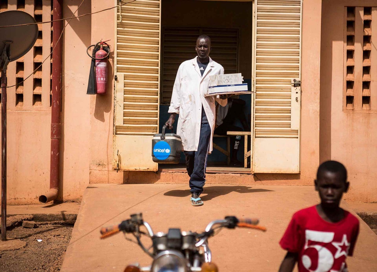 Adama Traoré, 40, a vaccinator, leaves the local community health centre with his vaccine box and other supplies. 