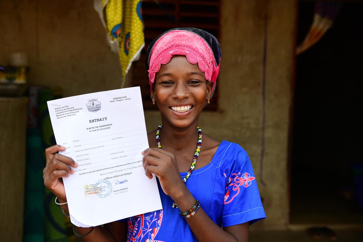 A young girl holds up her birth certificate. 