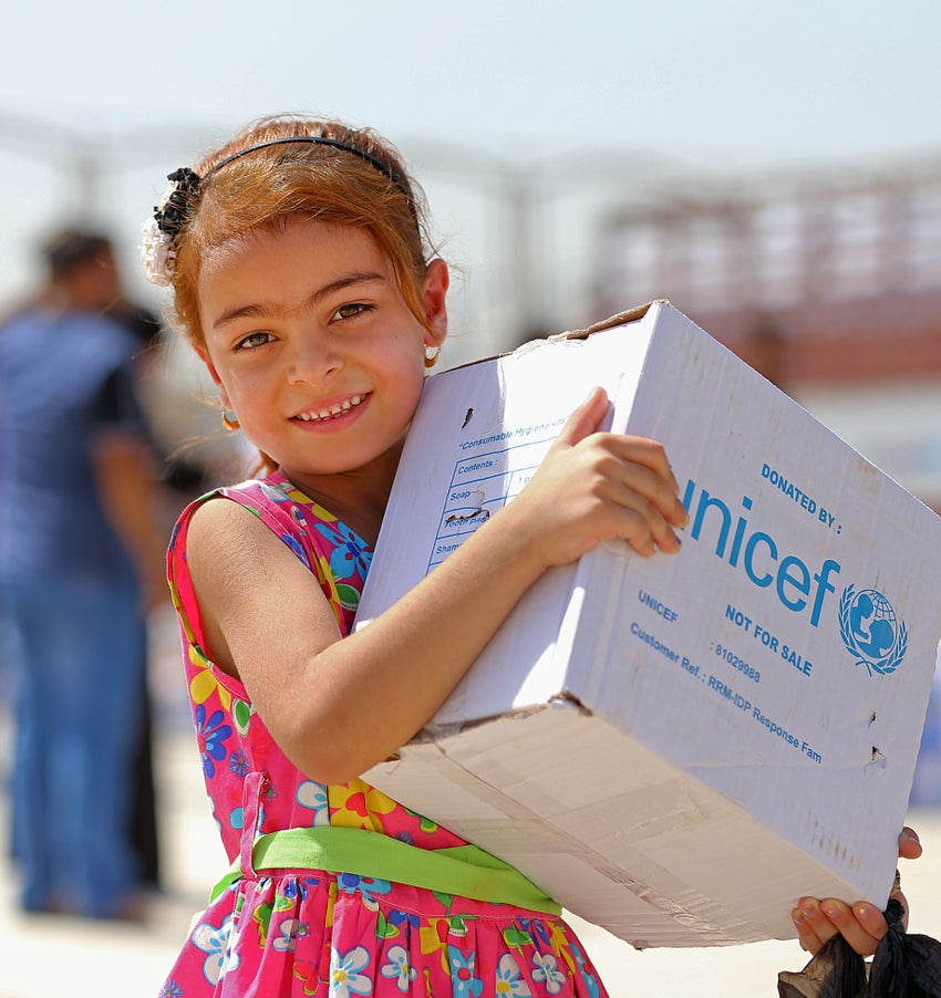 A young girl carrying a UNICEF box.