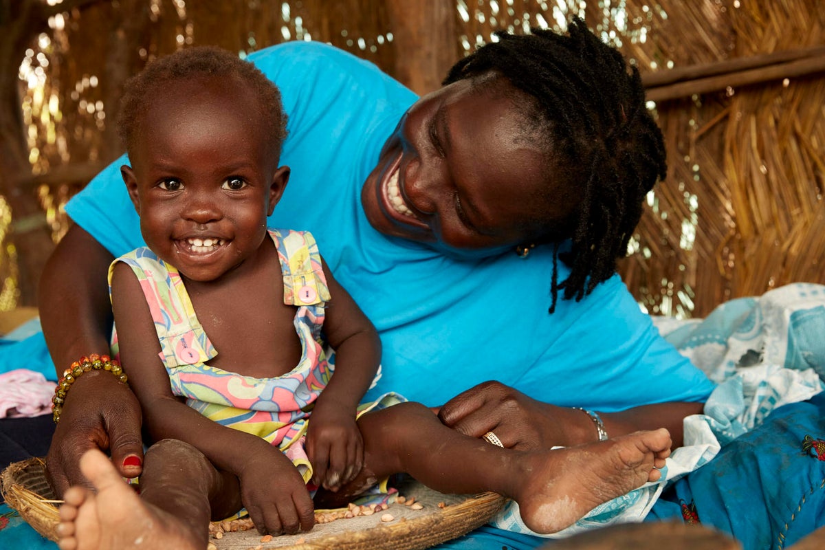 The toddler and the nutritionist are smiling and look very happy.