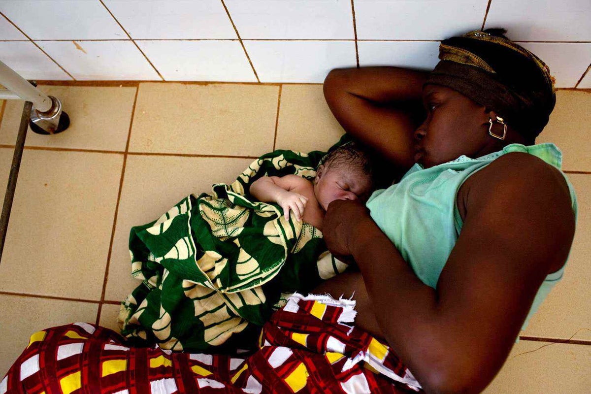 A new mother and her baby rest on the floor of their clinic in Guinea. A girl born in Guinea is twenty times less likely to celebrate her fifth birthday than if she was born here in Australia