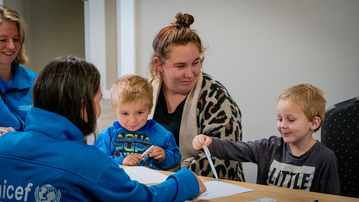 A mother sitting at a table with her two young sons. 