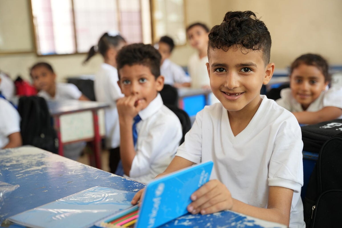 A young schoolboy smiles into the camera as he attends a school lesson using UNICEF school supplies.