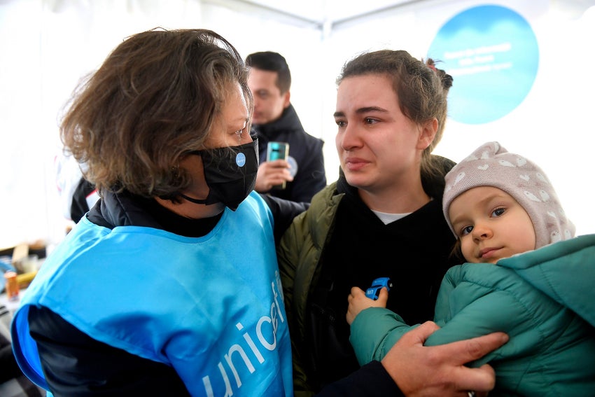 A UNICEF worker helping a mother and their child fleeing from the war in Ukraine. 